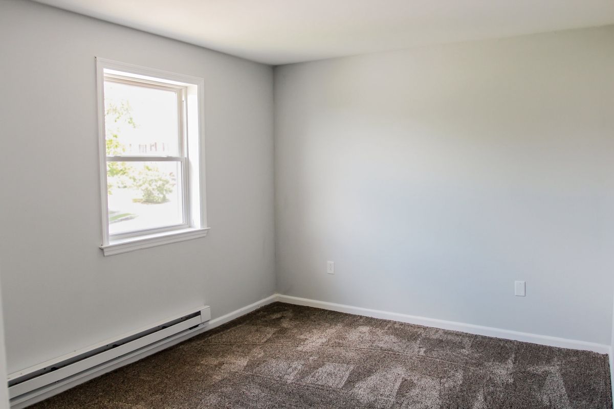 Painted bedroom with white window trim and baseboard heater