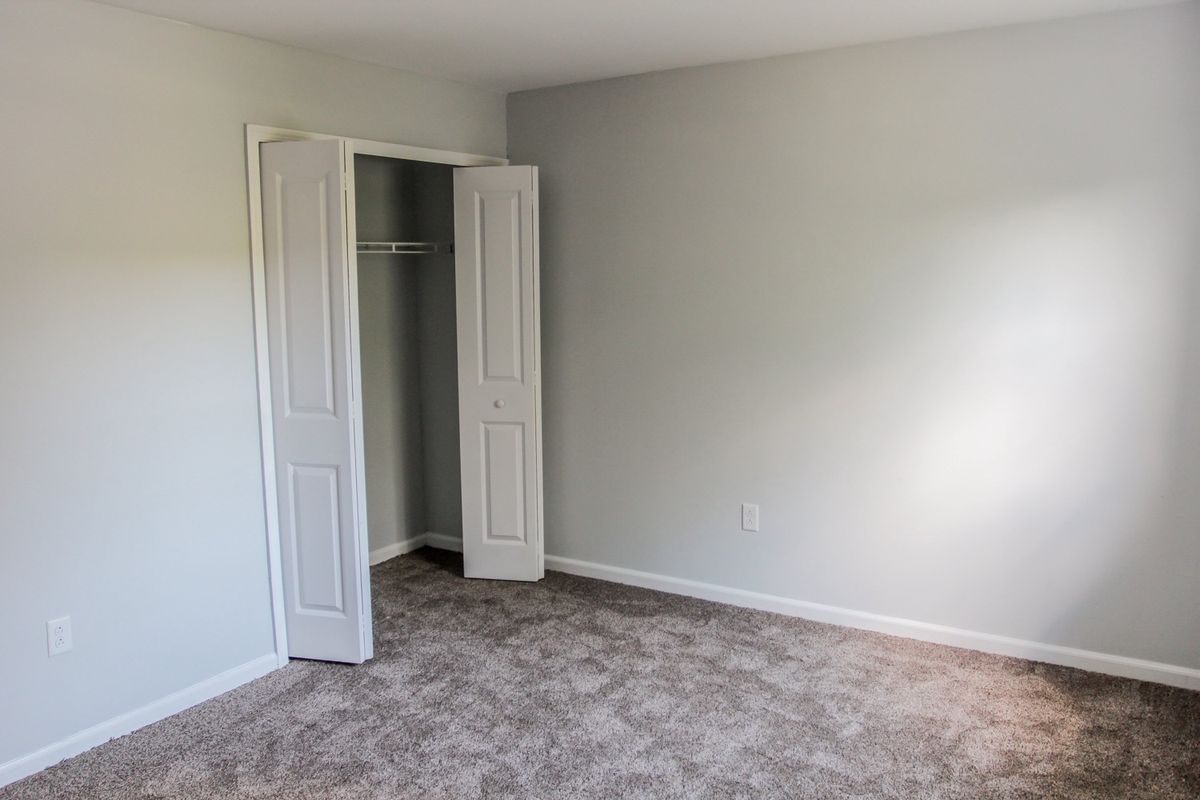 Freshly painted gray bedroom with white bifold closet doors and new carpet