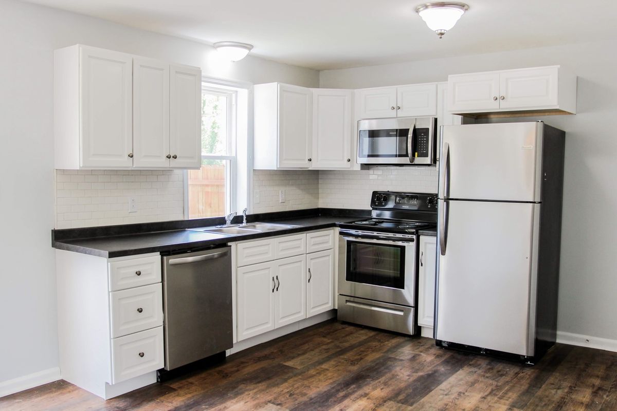 Renovated kitchen with white cabinets, subway tile backsplash and dark plank flooring in a Palmyra-area home
