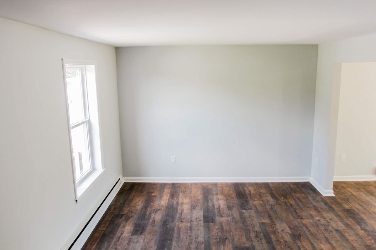 Freshly painted room with white window trim, baseboards and dark plank floor